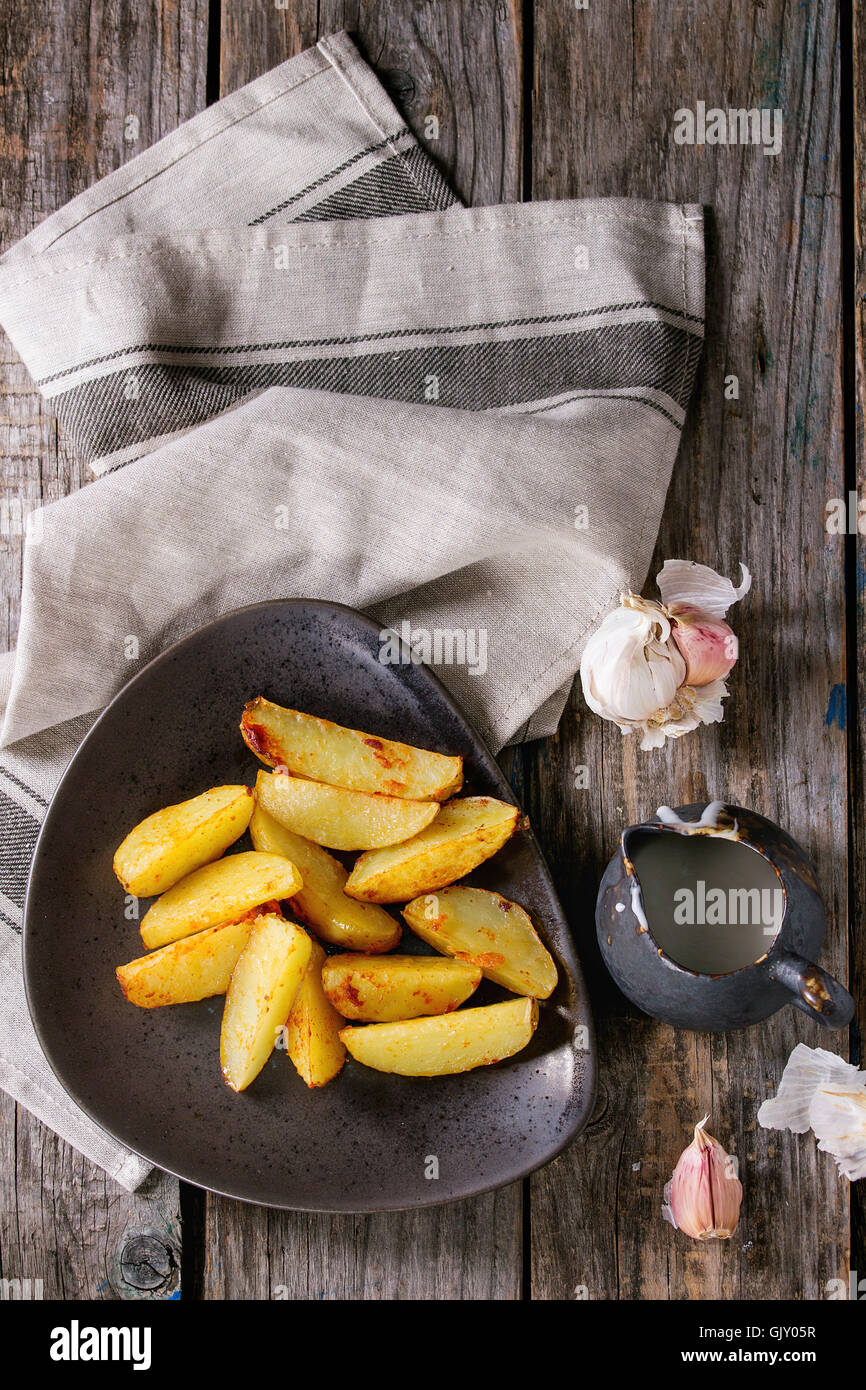 Land Bratkartoffeln auf braune Keramik-Platte, serviert mit hausgemachter Aioli Sauce in Krug, Knoblauch und Vintage Gabel auf Grau Leinen na Stockfoto