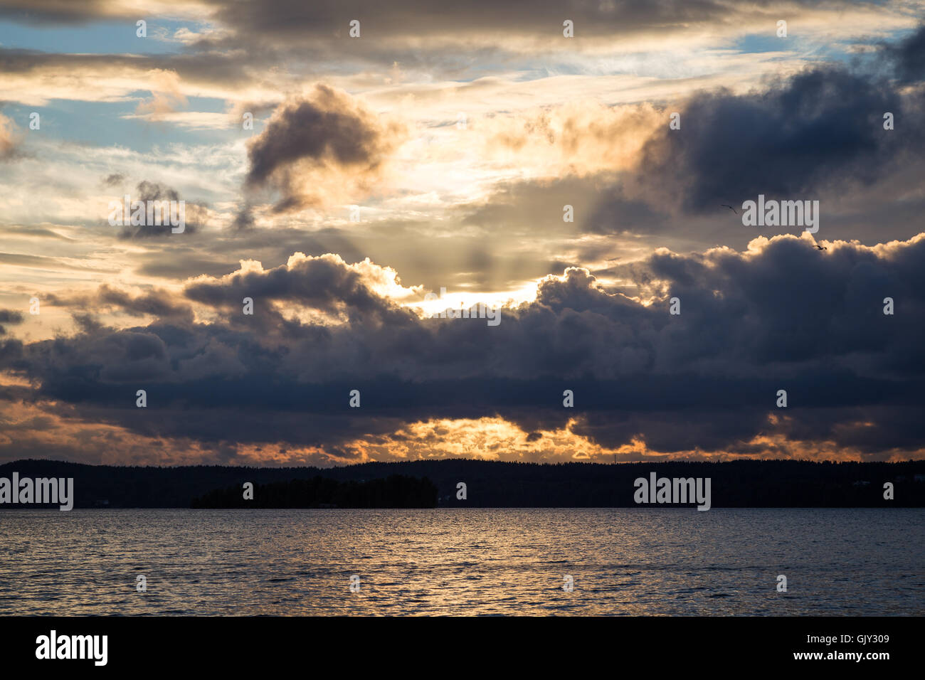 Blick auf dunkel und dramatische Wolken, Lichtstrahlen und einem See in Finnland bei Sonnenuntergang im Sommer. Stockfoto