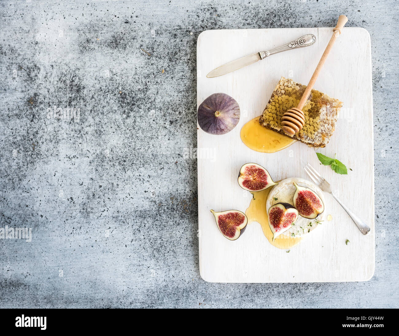 Camamber Käse mit Feigen und Honig Kamm auf weiß übermalt grauen Grunge Hintergrund, Draufsicht, Textfreiraum Holzbrett Stockfoto