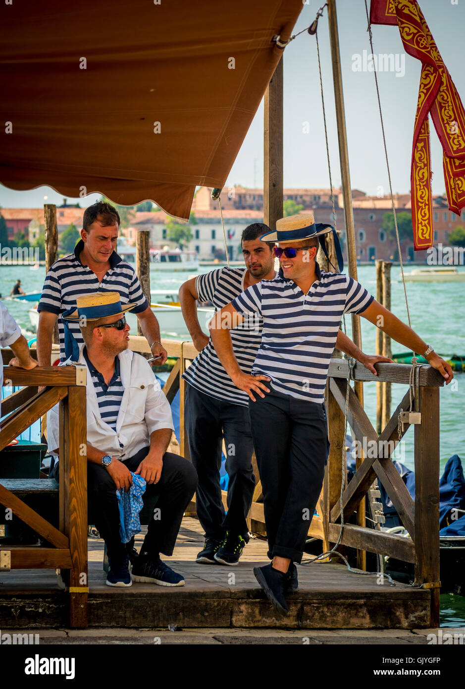 4 männliche Gondolieri tragen traditionelle gestreift Tops und Stroh Bootsfahrer hüten, warten auf Fahrgäste. Venedig, Italien. Stockfoto