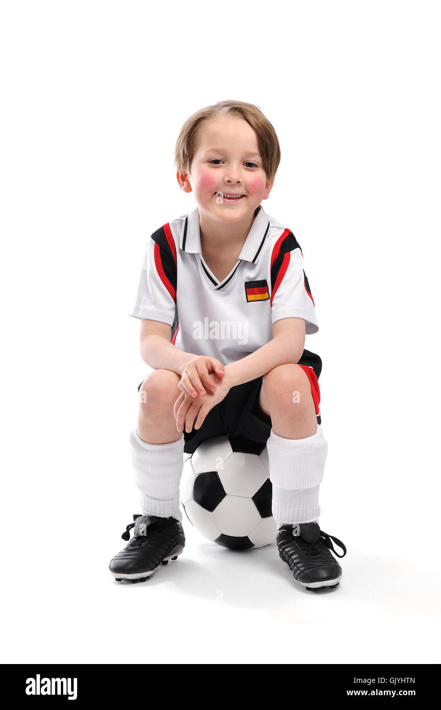 Junge sitzt auf einem Fußball Stockfoto