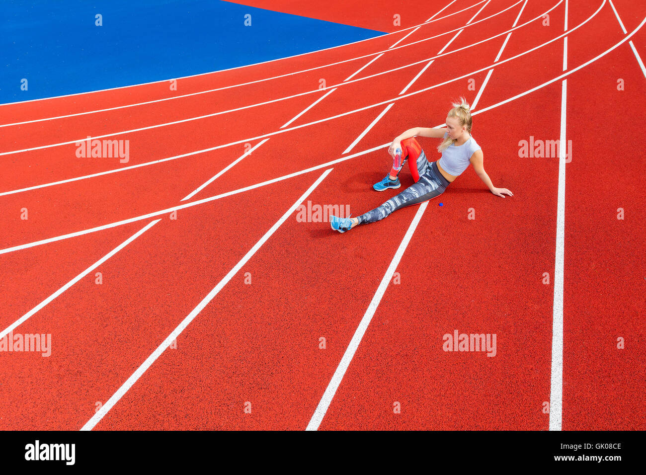 Athletische weibliche Läufer ruht auf Laufstrecke in Sportarena Stockfoto