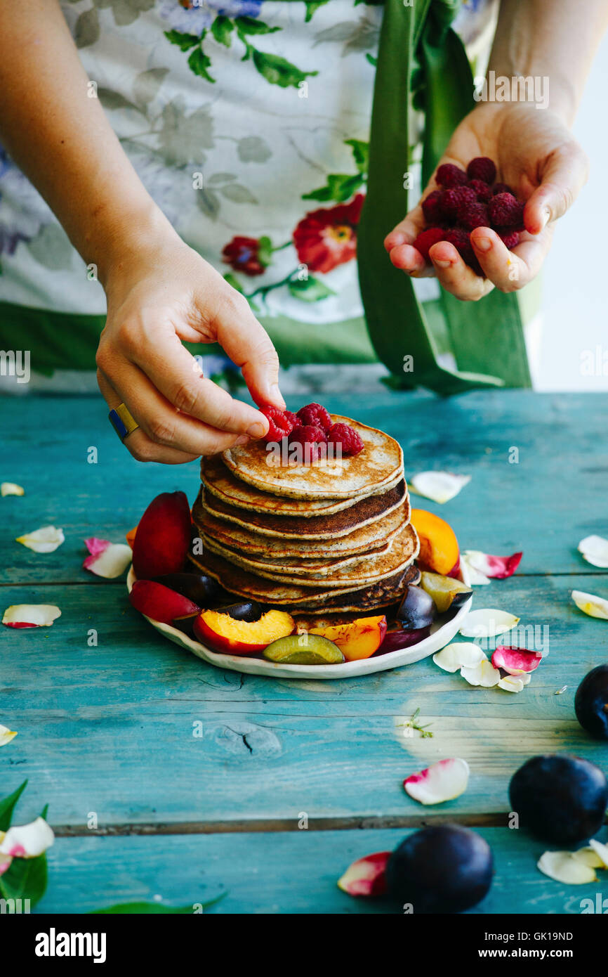 Mädchen, die Himbeeren auf der Oberseite Pfannkuchen setzen Stockfoto