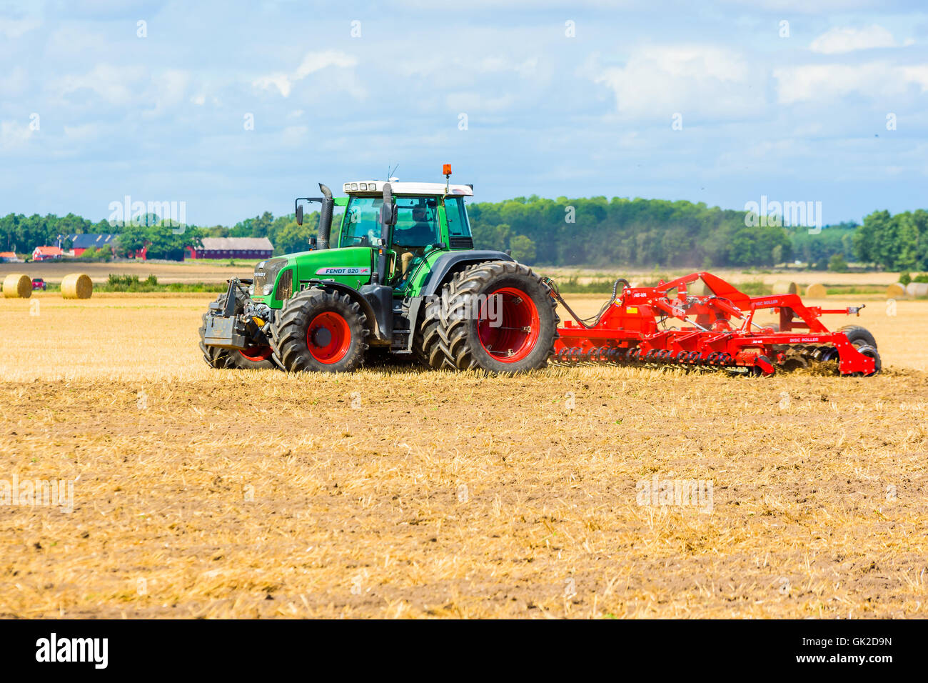 Kalmar, Schweden - 10. August 2016: Landwirt Scheibe Feld mit grünen Fendt 820 Traktor ins Rollen. Bauernhof und Wald im Hintergrund. Stockfoto