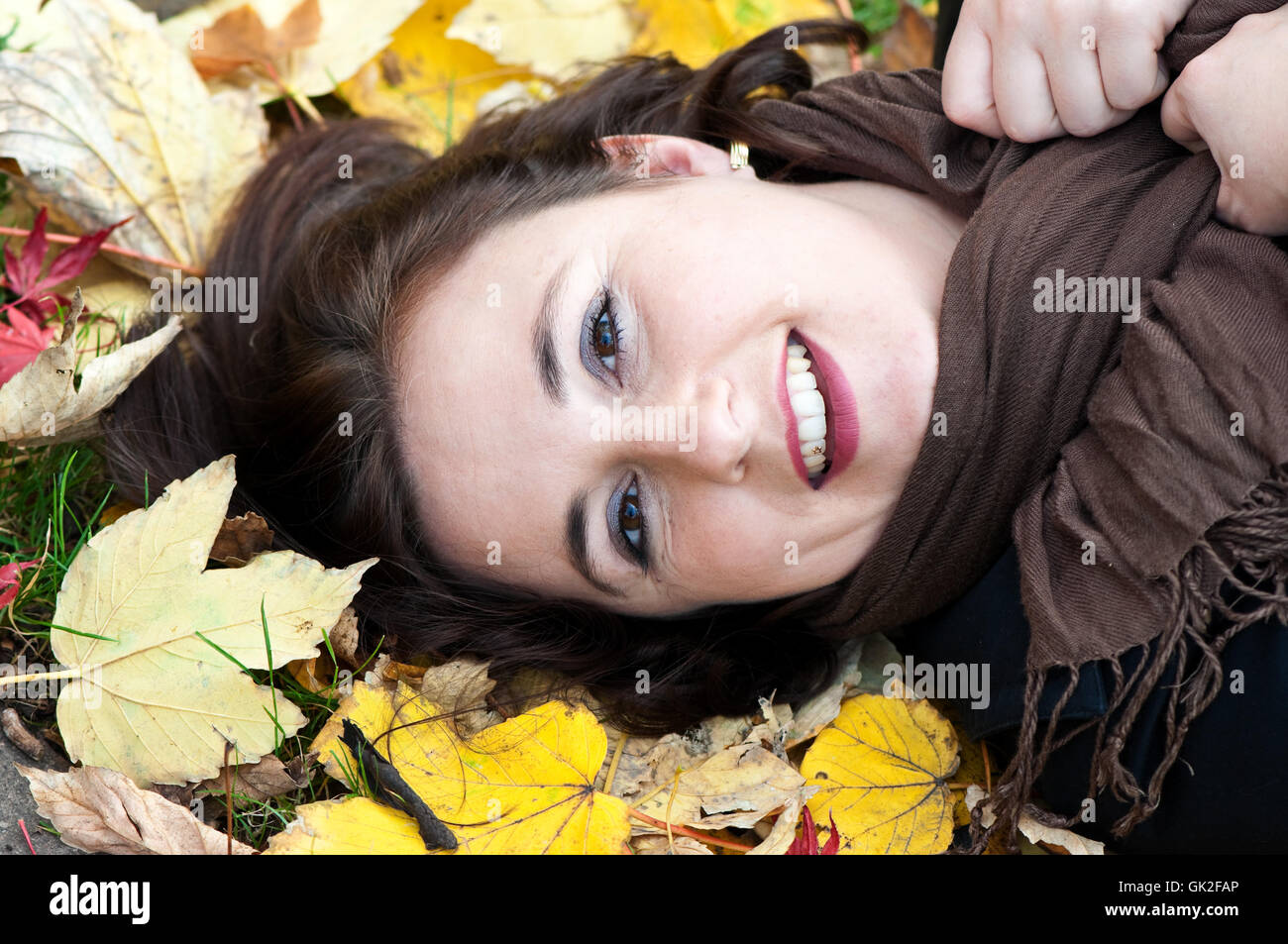 junge Frau im Herbstlaub liegend Stockfoto