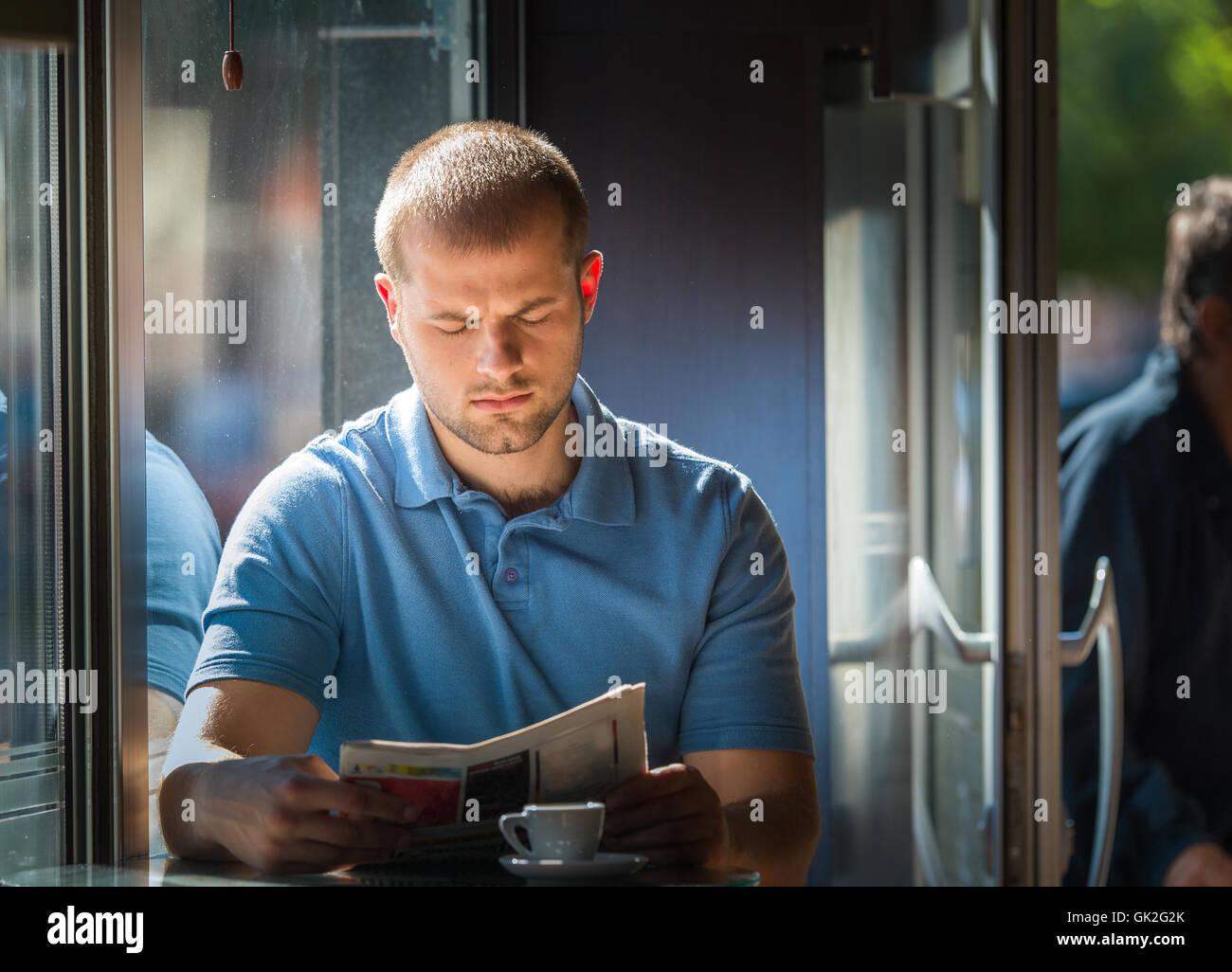 junger Mann liest eine Zeitung in einem café Stockfoto