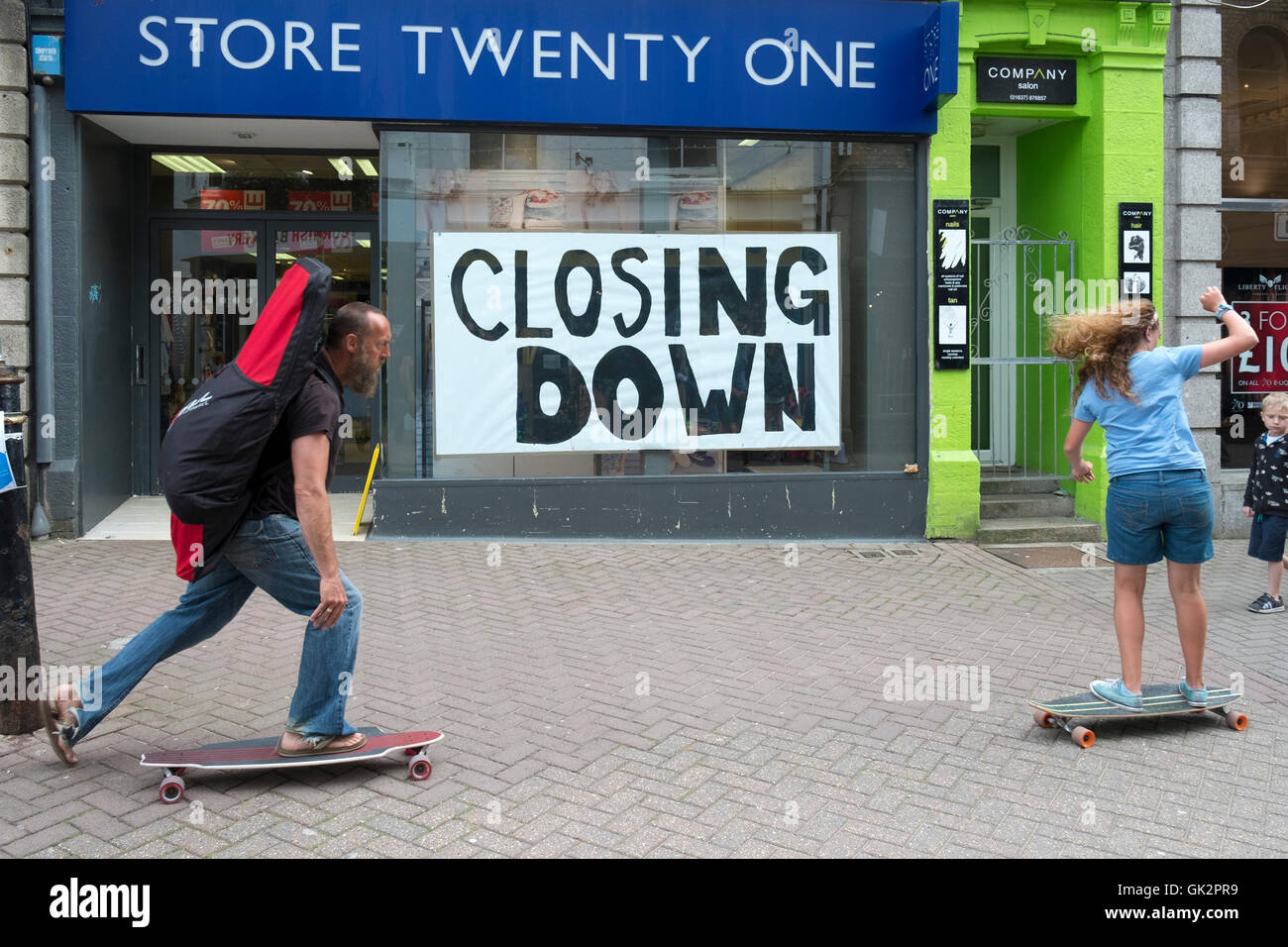 Skateboarder Skaten an einem Geschäft unten schließen im Stadtzentrum von Newquay, Cornwall, England, Großbritannien. Stockfoto