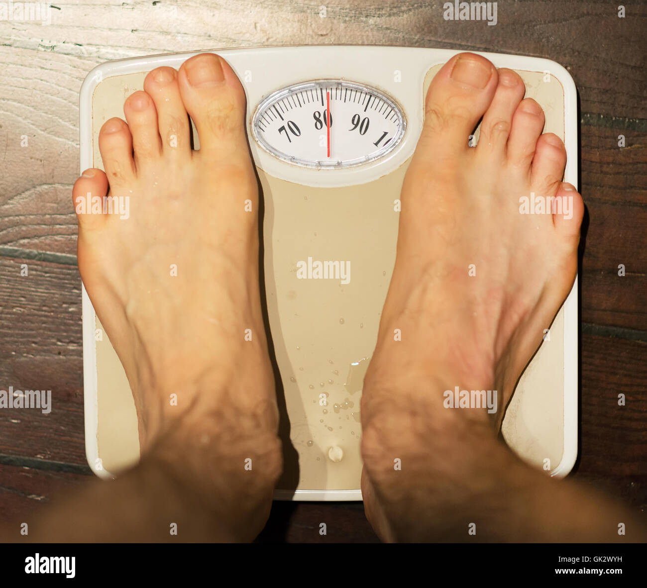 Mann steht auf Waage im Badezimmer. Ca. 80 kg. Stockfoto