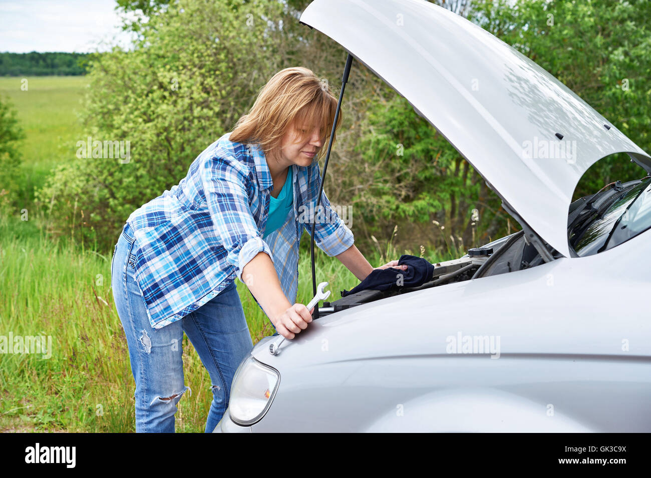 Frau, die versucht, kaputtes Auto selbst zu reparieren Stockfoto