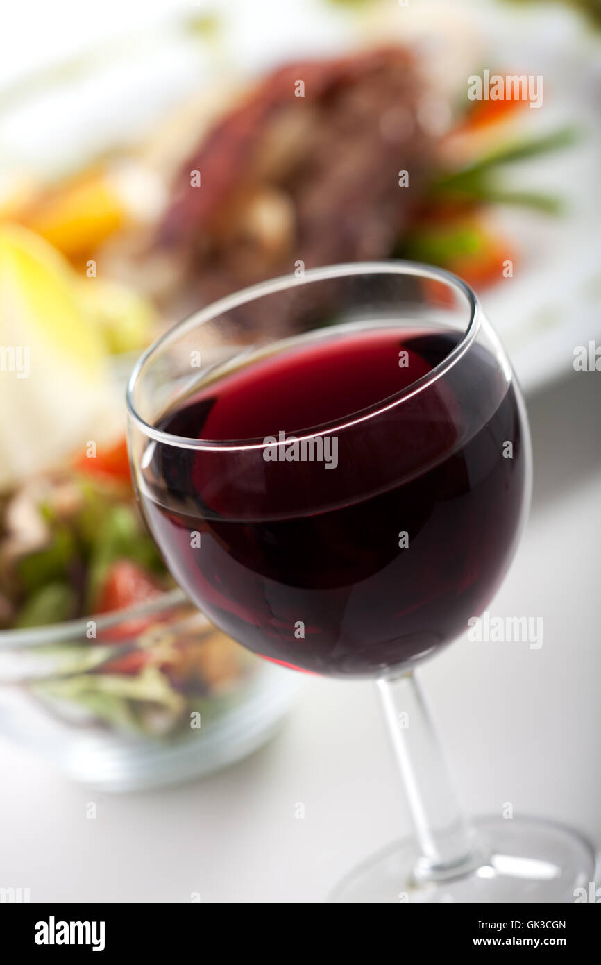 Glas Rotwein und Abendessen Stockfoto