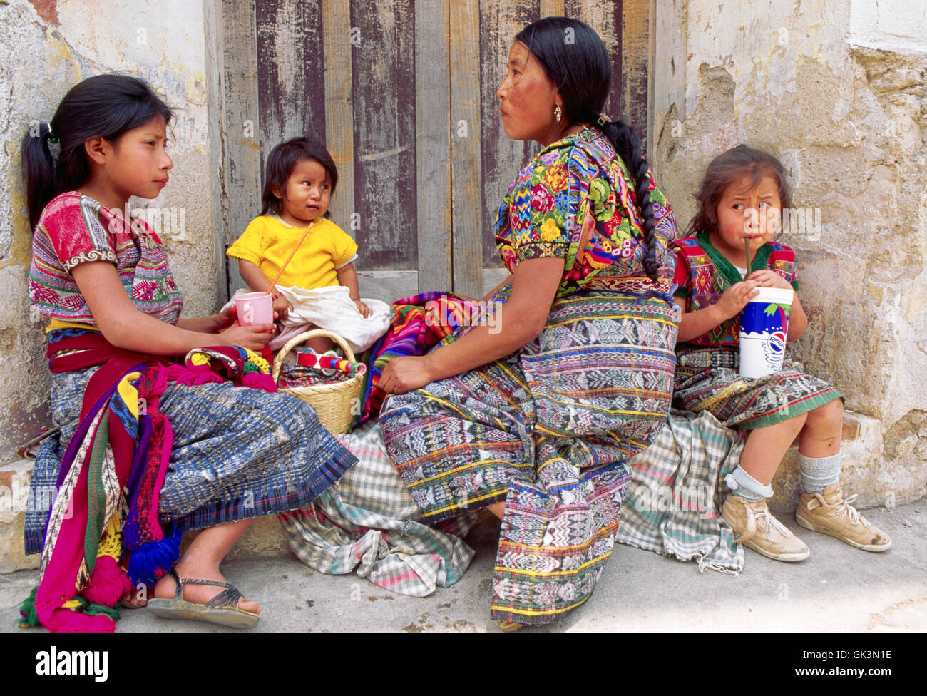 ca. 1980-1995, Guatemala---eine Maya-Familie sitzen alle gekleidet bunte Kleidung, in ein Tor zu essen und zu trinken. Guatem Stockfoto