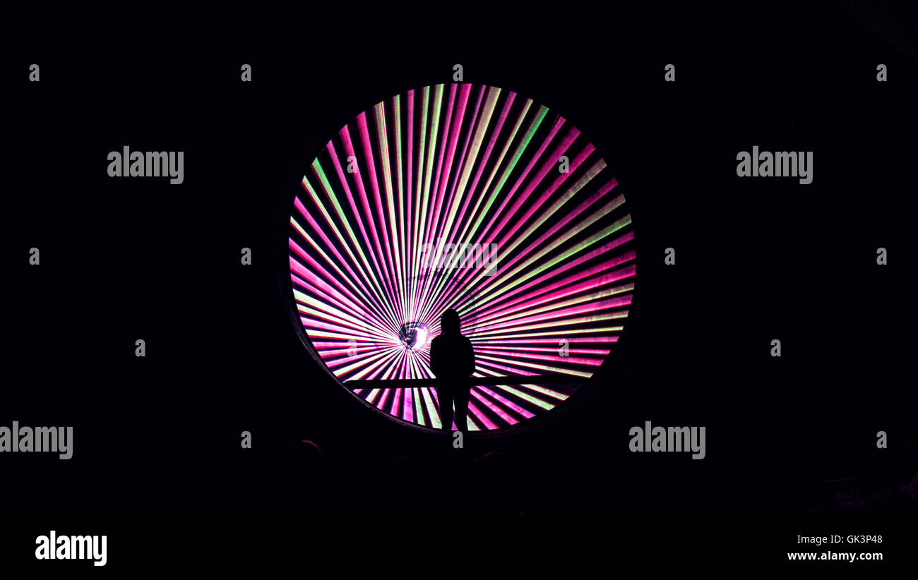 menschliche Silhouette in der Mitte des kreisförmigen Laserinstallation grün und Rosa Linien, Stockfoto