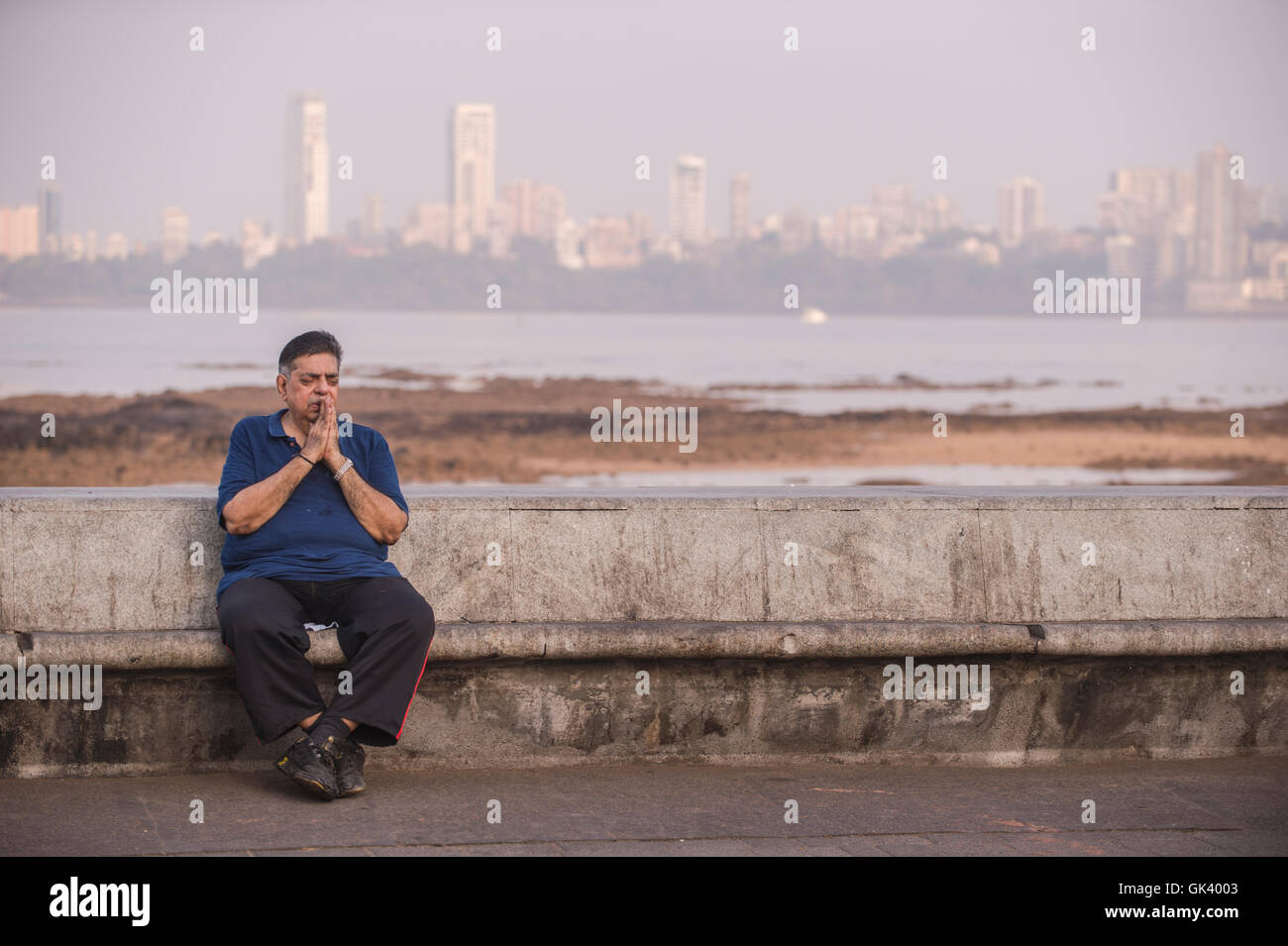 Ein indischer Mann betet, wie er auf einer Bank in Mumbai, Indien-Credit sitzt: Euan Cherry Stockfoto