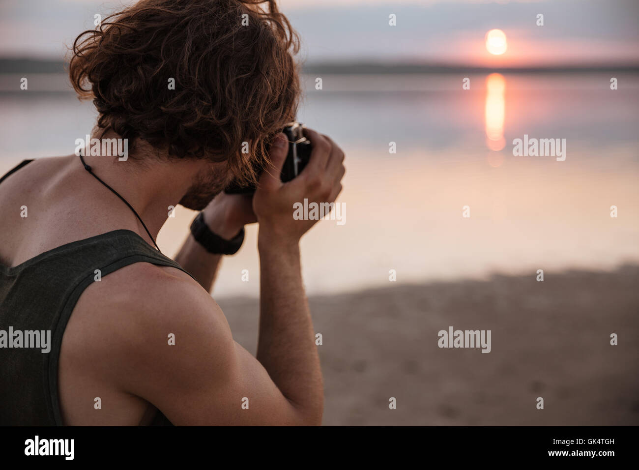 Junger Mann machen Foto des Sonnenuntergangs mit Kamera im freien Stockfoto