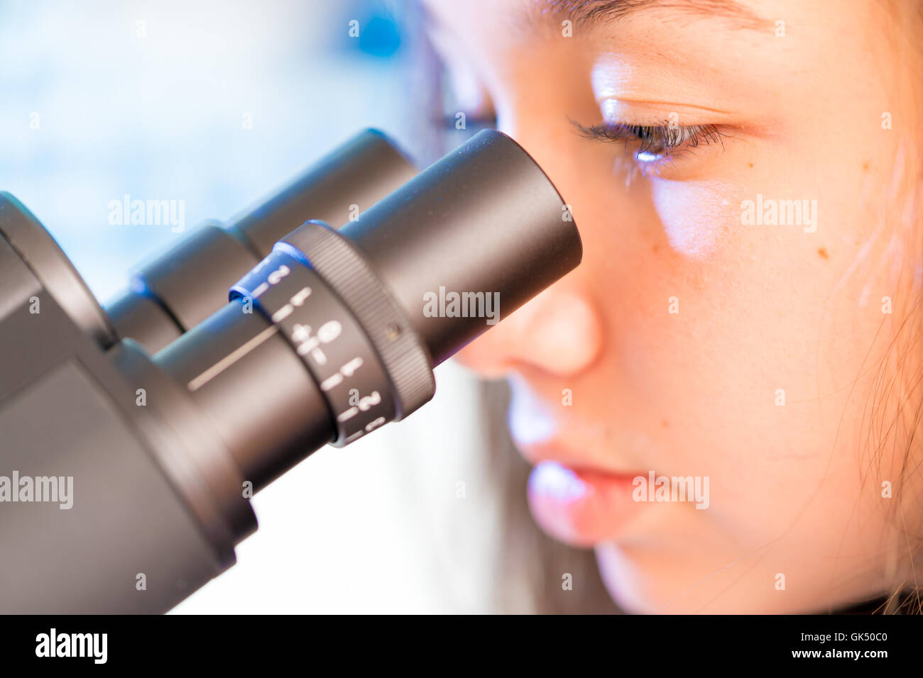 Biologie-Unterricht. Weibliche Teenager-Studentin im naturwissenschaftlichen Unterricht mit Experiment am Mikroskop Stockfoto