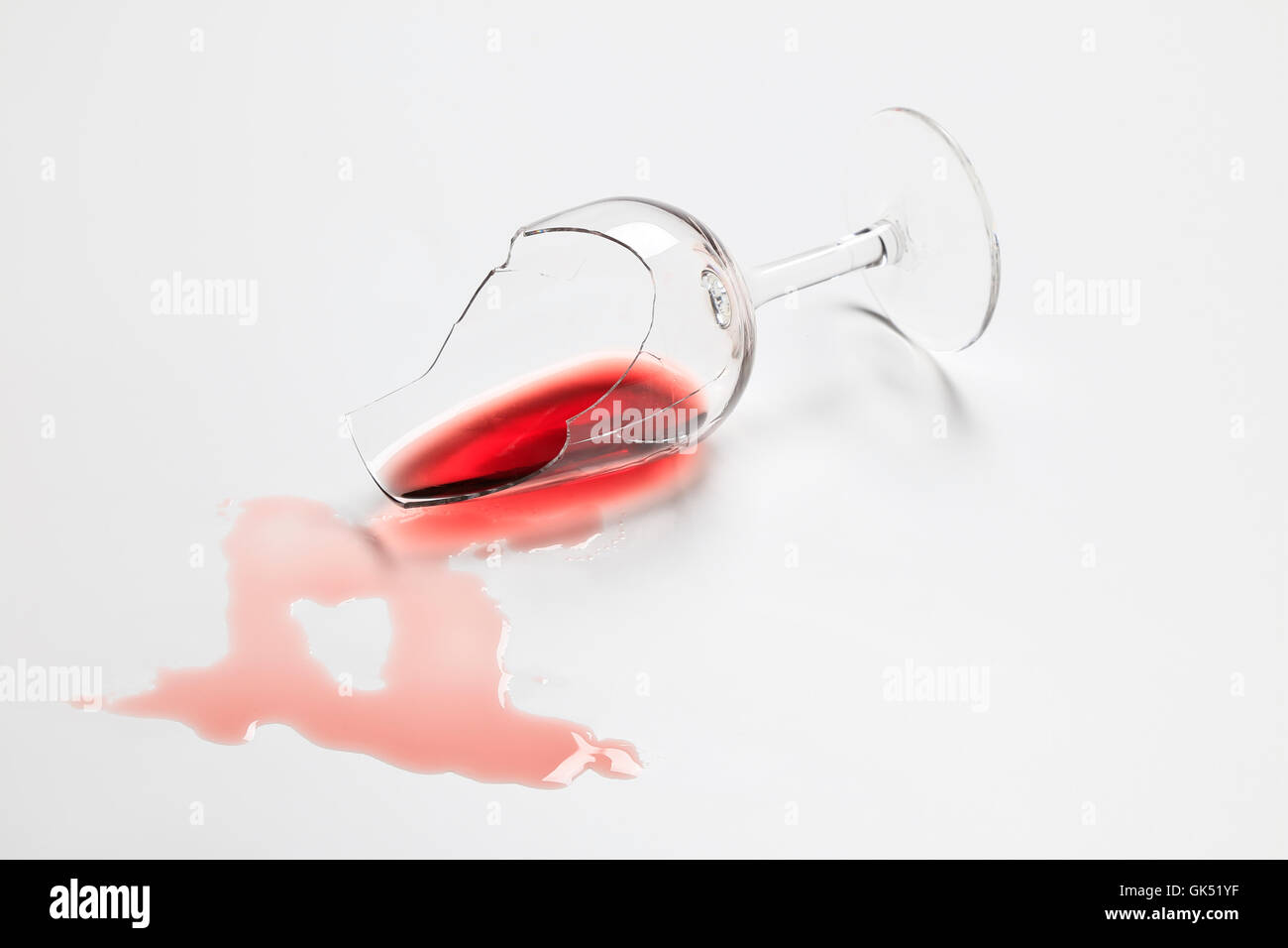 Gebrochener roter Wein Tasting Glas mit Wein auf weißem Hintergrund Stockfoto