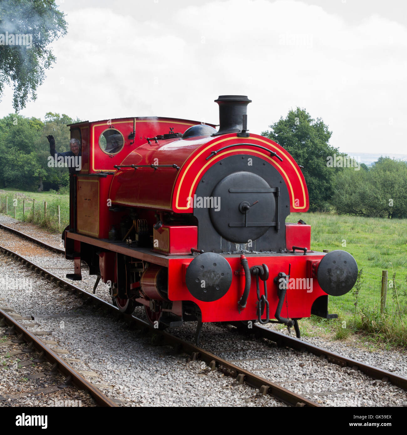 Die Wellen der Fahrer aus der Kabine eine industrielle 0-4-0 Sattel Tank Dampfmaschine in rot auf der Foxfield Eisenbahn Lokomotive. Stockfoto