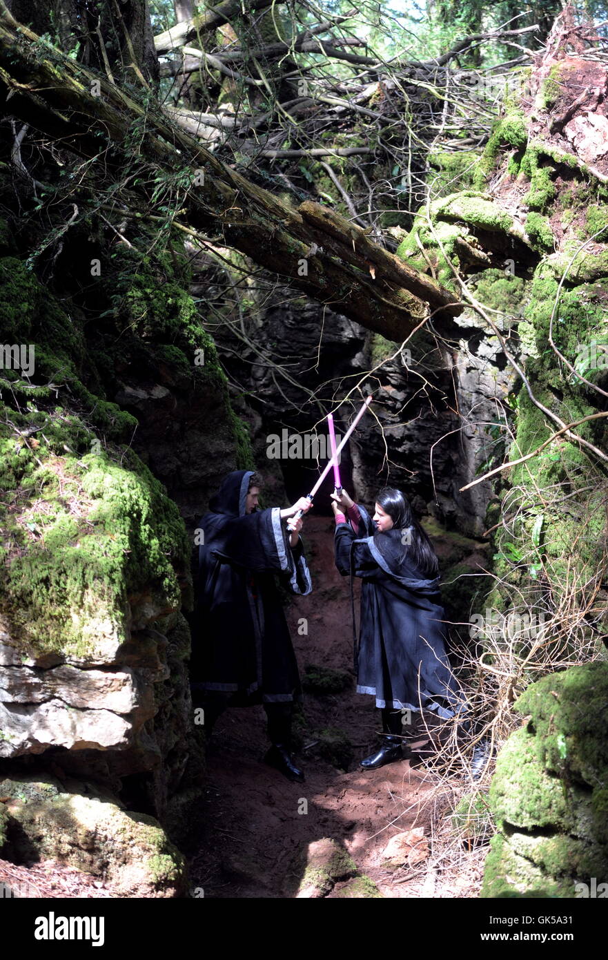 Farahziya Ziya und Dan Walton von der Star Wars Lightsaber Combat Academy ausleben einer Schlacht mit vorgeben Lichtschwerter in Puzzlewood, einer alten Wald in Gloucestershire, England, wo Star Wars: das Erwachen der Macht wurde gefilmt.  Die Schlacht fand während einer Stockfoto
