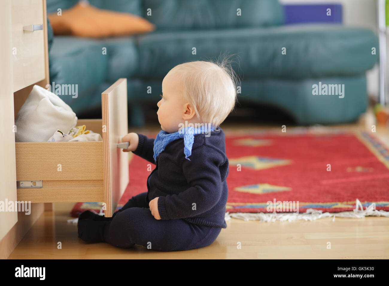 Kleiner Junge versucht zu öffnen und hineinschauen Schublade Brust. Stockfoto