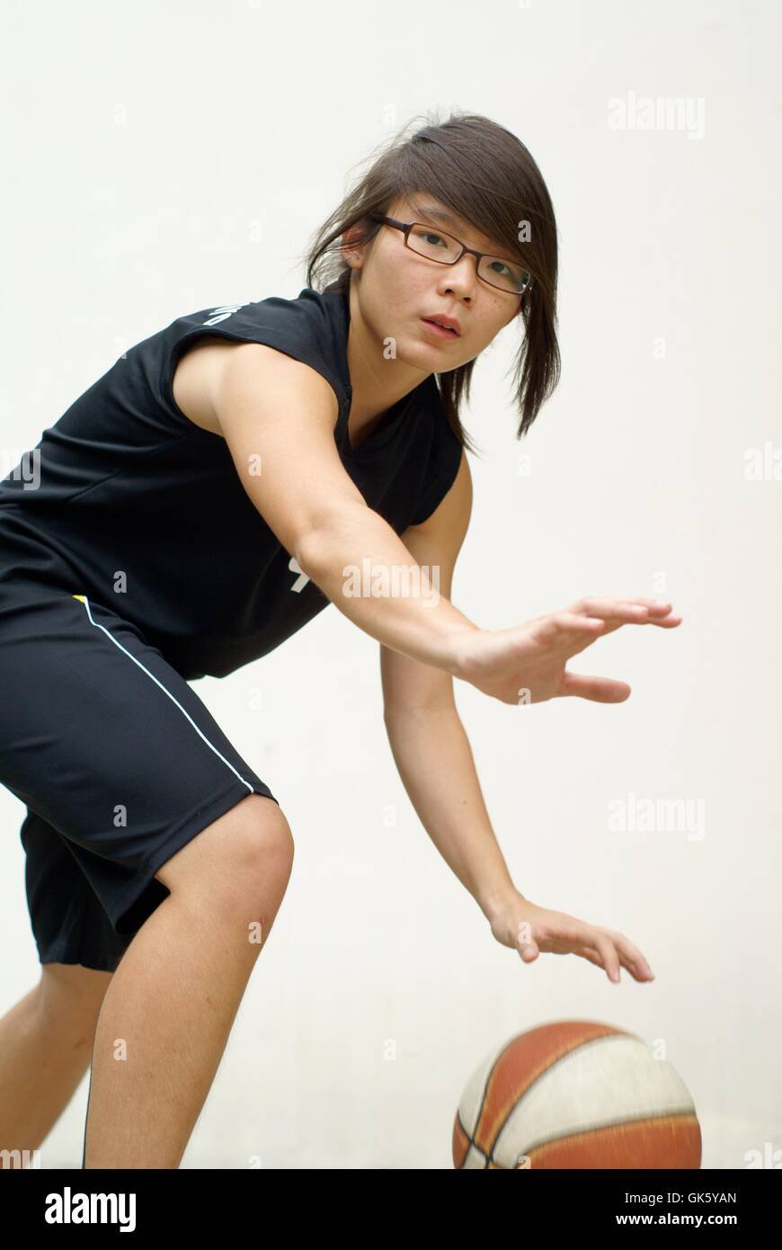 Gesunde asiatische Basketballspieler, die Kugel zu verteidigen Stockfoto