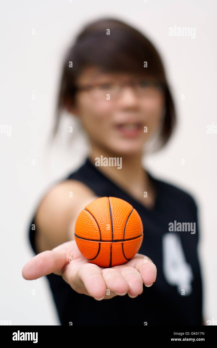 Asiatische Teen halten kleine orange Basketball in der hand Stockfoto