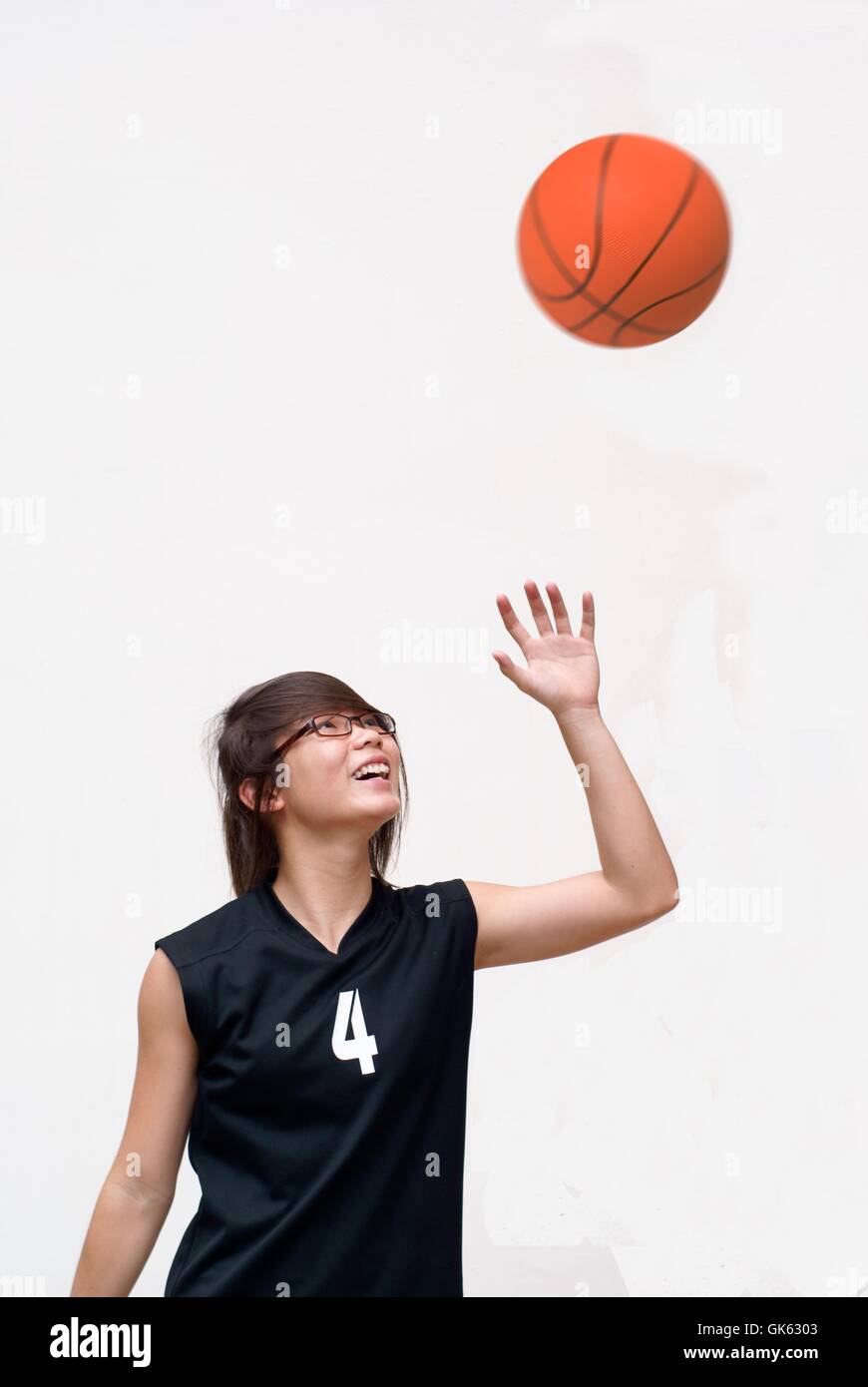 Glücklich asiatischen weiblichen Teenager Basketballspieler blickte zu ball Stockfoto