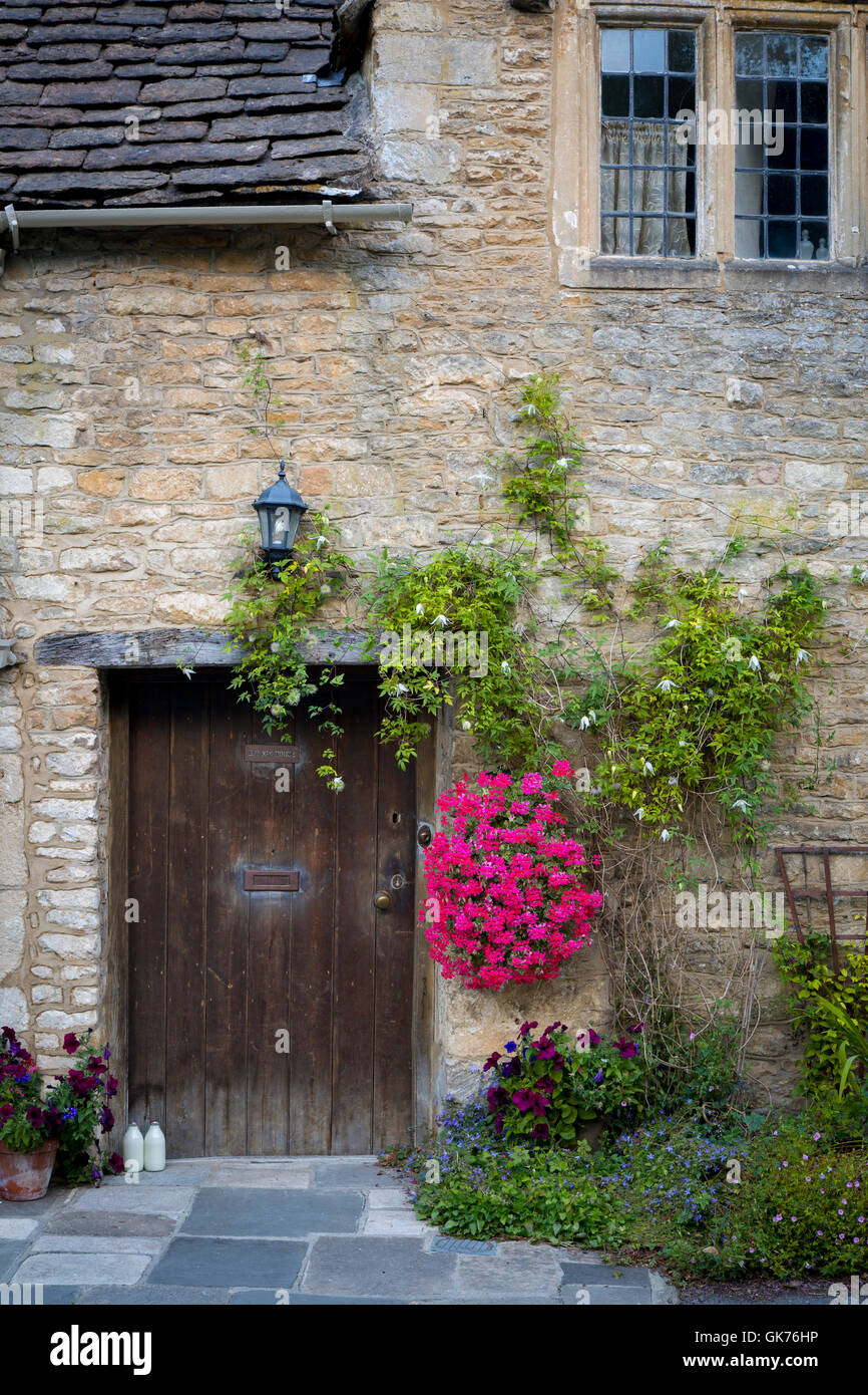 Milchflaschen an vor der Tür der Hütte in Castle Combe, die Cotswolds, Wiltshire, England Stockfoto