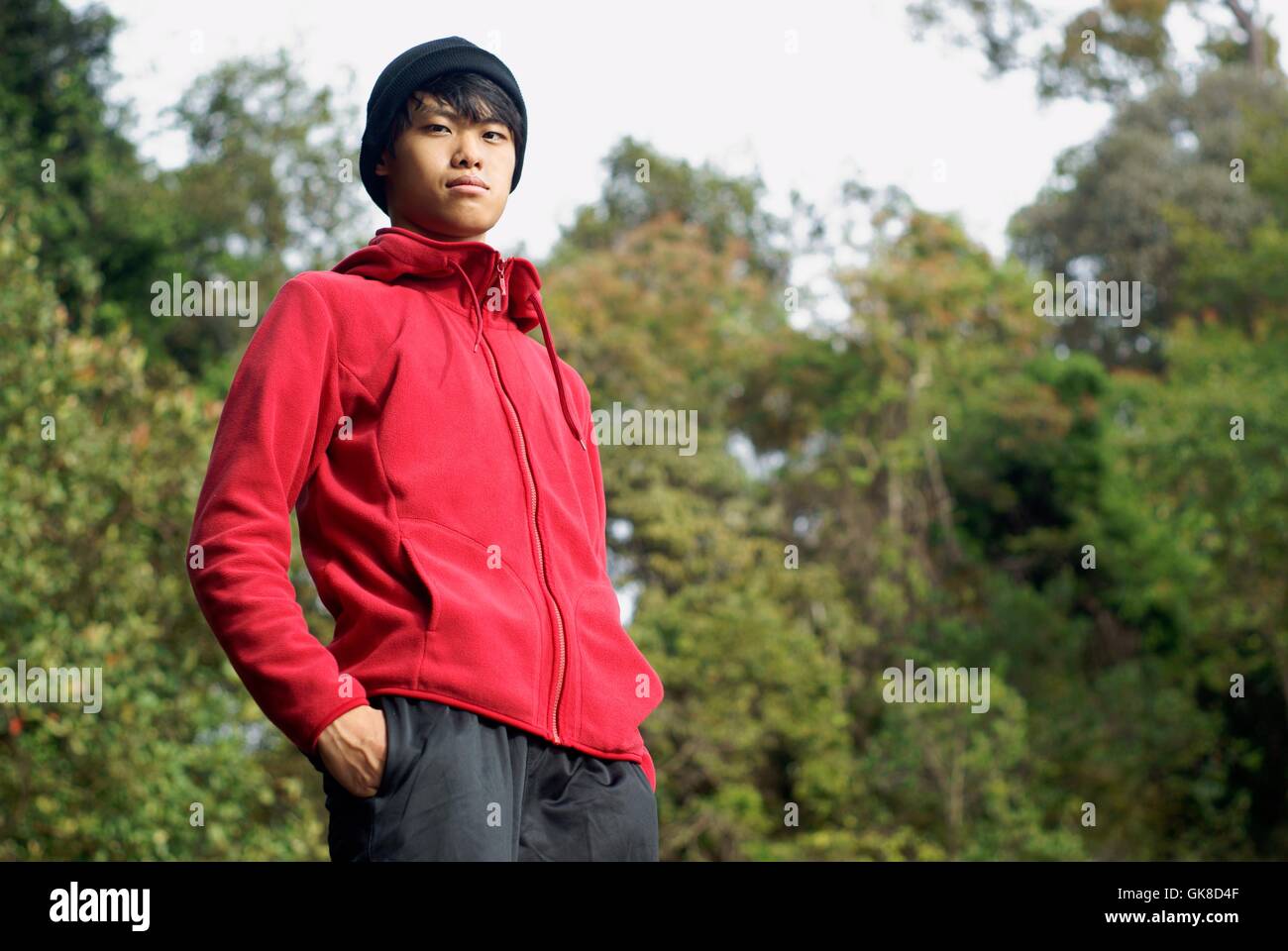 Zuversichtlich asiatischer Mann draußen im roten Pullover Stockfoto