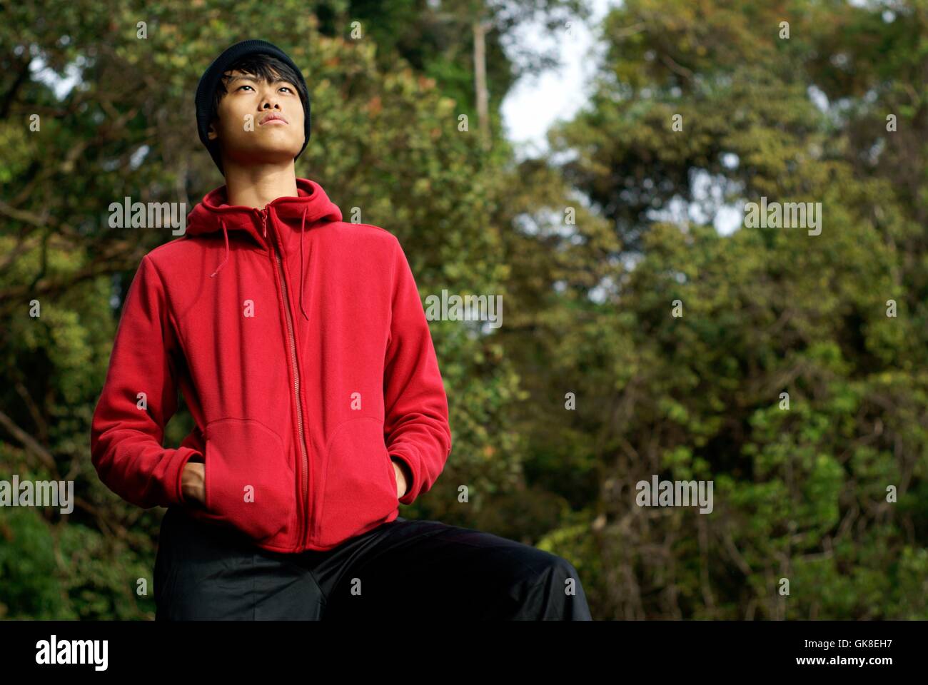 Asiatischer Mann im roten Pullover im freien nachschlagen Stockfoto