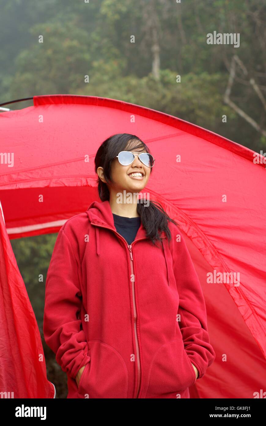 Gerne Asiatin mit Sonnenbrille mit roten Zelt im freien Stockfoto