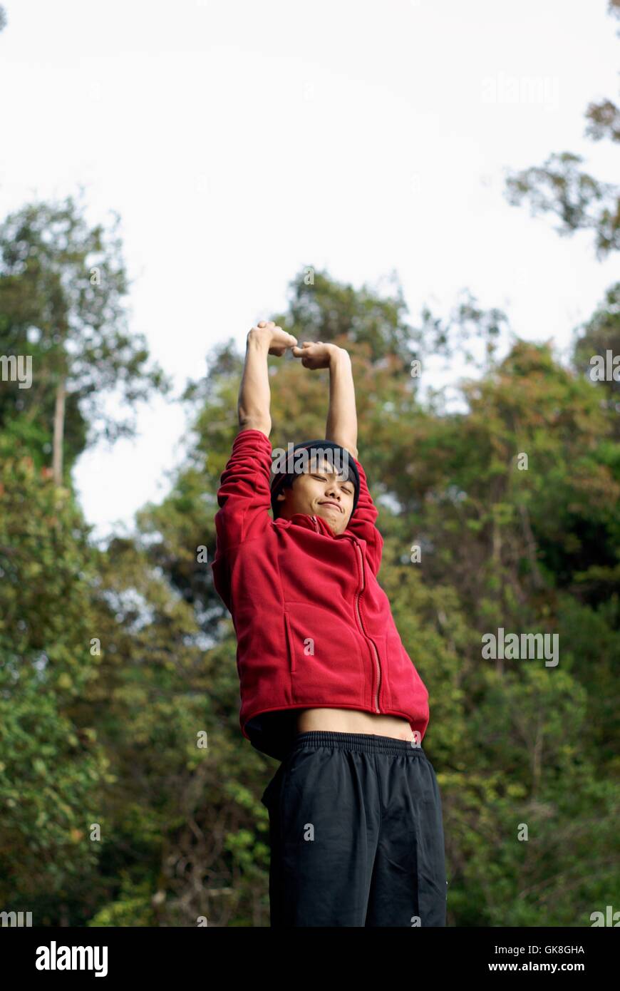 Glücklich asiatischer Mann streckte Arme oben im freien Stockfoto