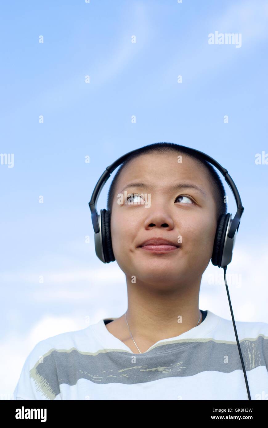 Glücklich kahle asiatische Mädchen mit Kopfhörern im freien Stockfoto