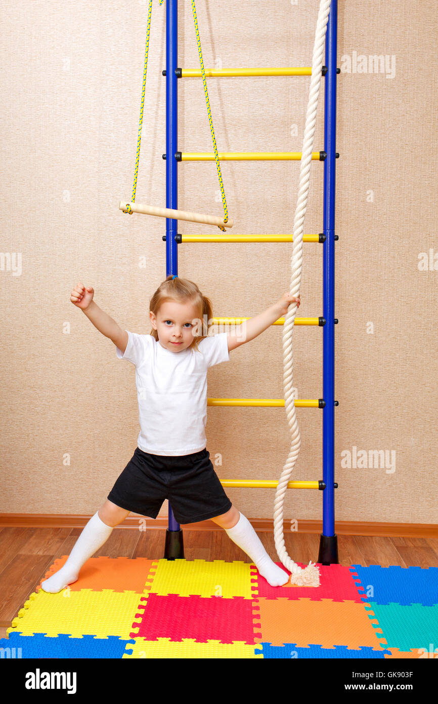 Kleines Mädchen posiert neben der Sprossenwand. Sportgeräte. Sportangebot  für Kinder Stockfotografie - Alamy