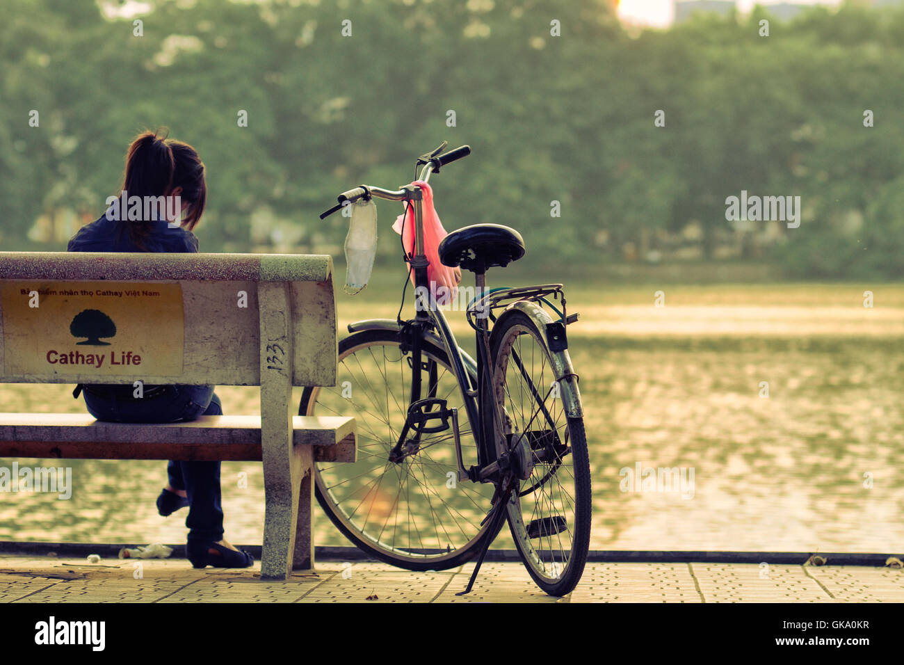 Hanoi, Vietnam - 28. August 2011: das Mädchen sitzt auf der Bank neben ihr Fahrrad am Hoan-Kiem-See Stockfoto