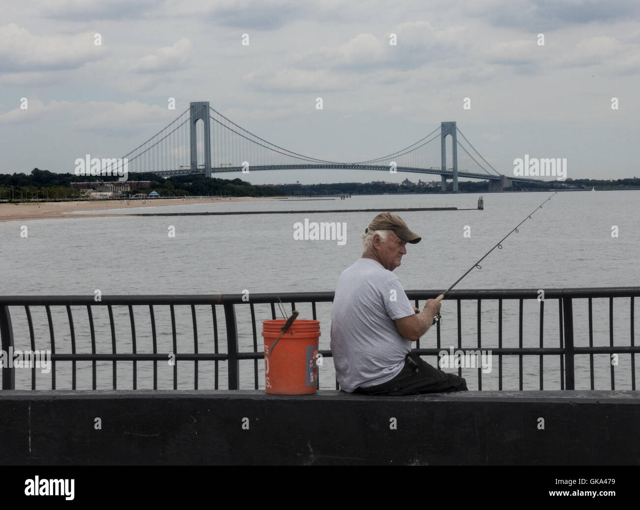 Alte Fischer Angeln auf der Mole in South Beach, Staten Island mit der Verrazano-Brücke in der Ferne. NEW YORK CITY Stockfoto