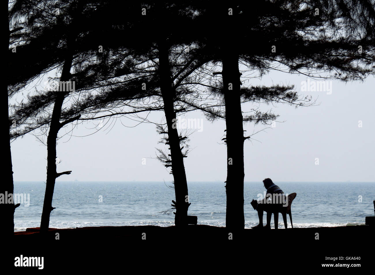 Eine Silhouette eines Mannes friedlich ein Buch am Strand während seiner Sommerferien. Stockfoto