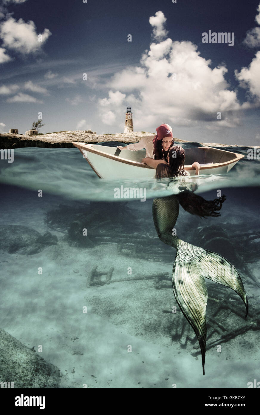 Junge Frau Pirate Interaktion mit einer Meerjungfrau aus ihrem Schlauchboot Stockfoto