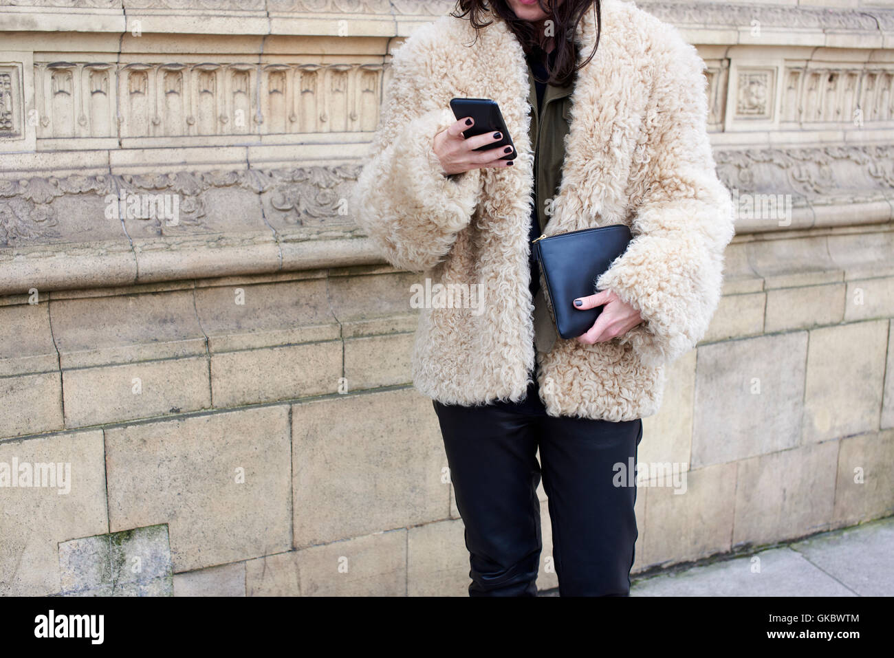 Frau mit Lammfell Jacke mit Smartphone, Ernte Stockfoto