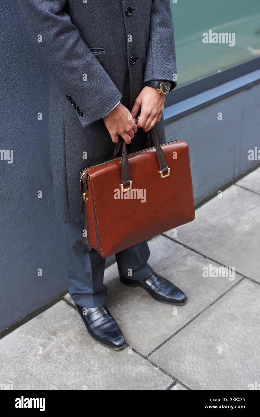 Mann im grauen Mantel hält braune Aktentasche, Ernte Stockfoto