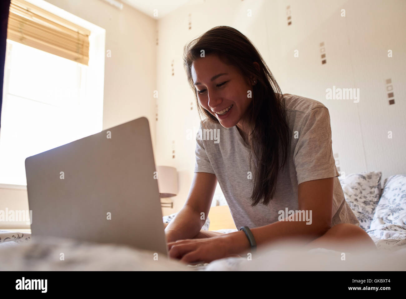 Frau sitzt auf dem Bett mit Laptop-Computer Stockfoto