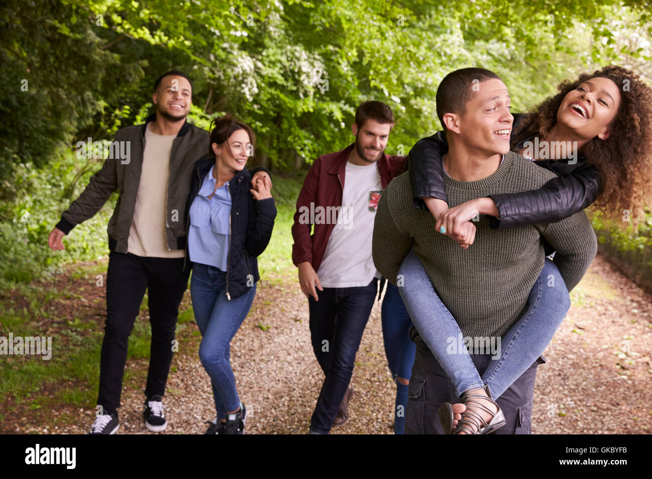 Glückliche Freunde zu Fuß und in einen Feldweg Huckepack Stockfoto