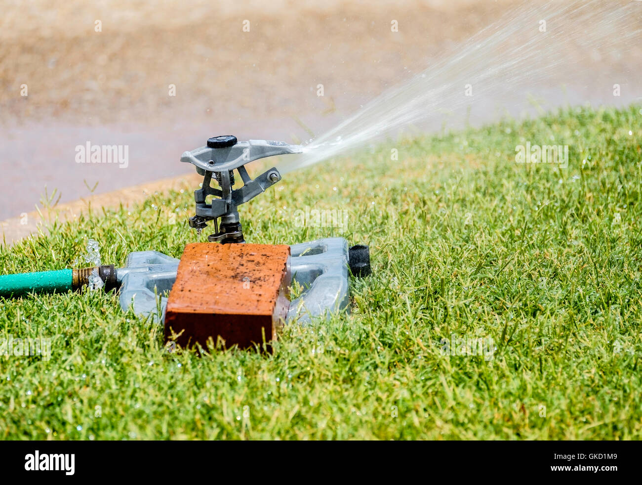 Eine Sprinkleranlage gehalten durch einen Ziegelstein Wasser Rasen während einer heißen und trockenen Sommer in Oklahoma City, Oklahoma, USA. Stockfoto