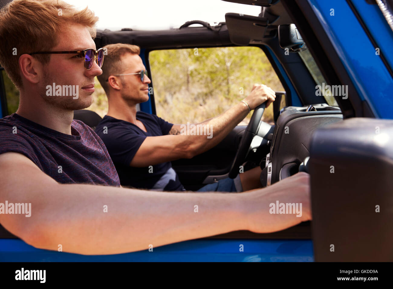 Zwei männliche Freunde fahren offene Top Auto auf Landstraße Stockfoto