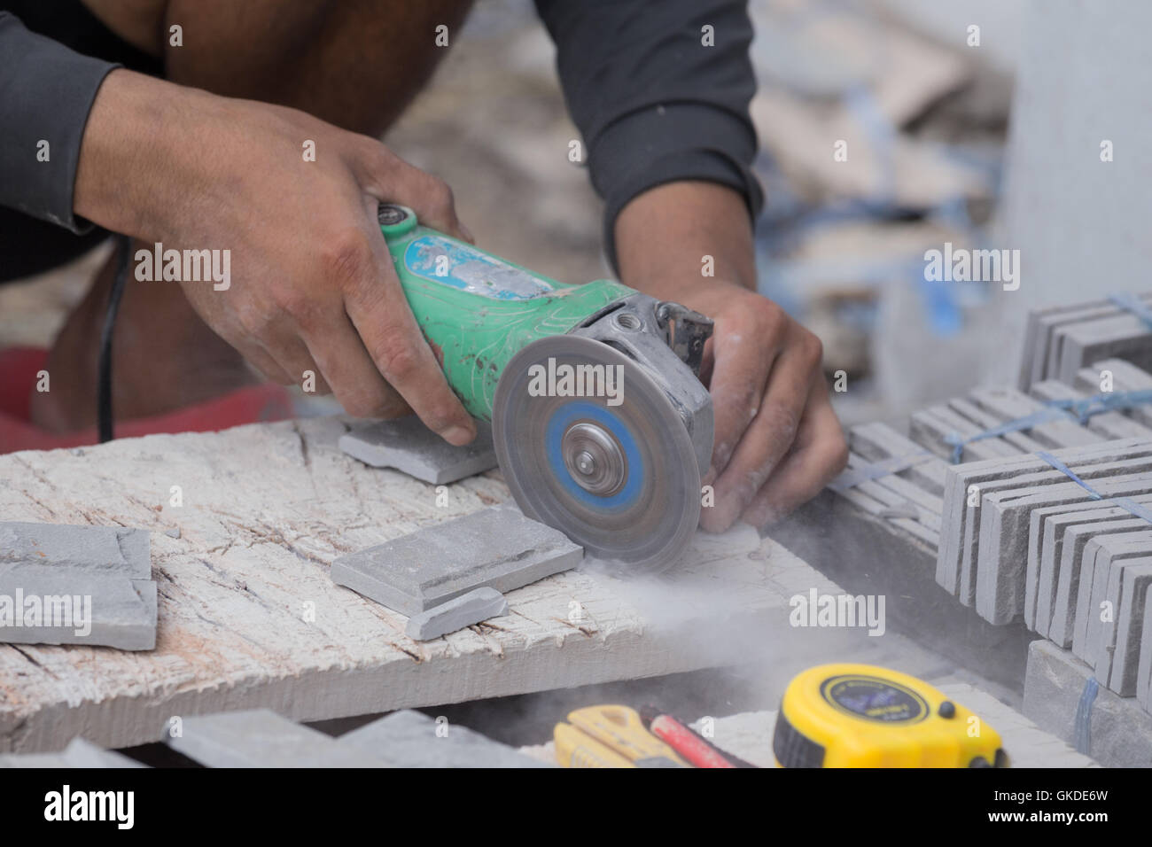 Arbeiter schneiden ein Sandstein Fliesen mit einem Winkelschleifer auf Baustelle Stockfoto