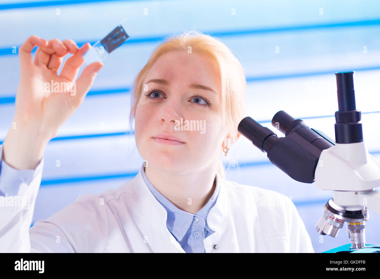 junge Frau mit Mikroskop-Objektträger im Labor Stockfoto