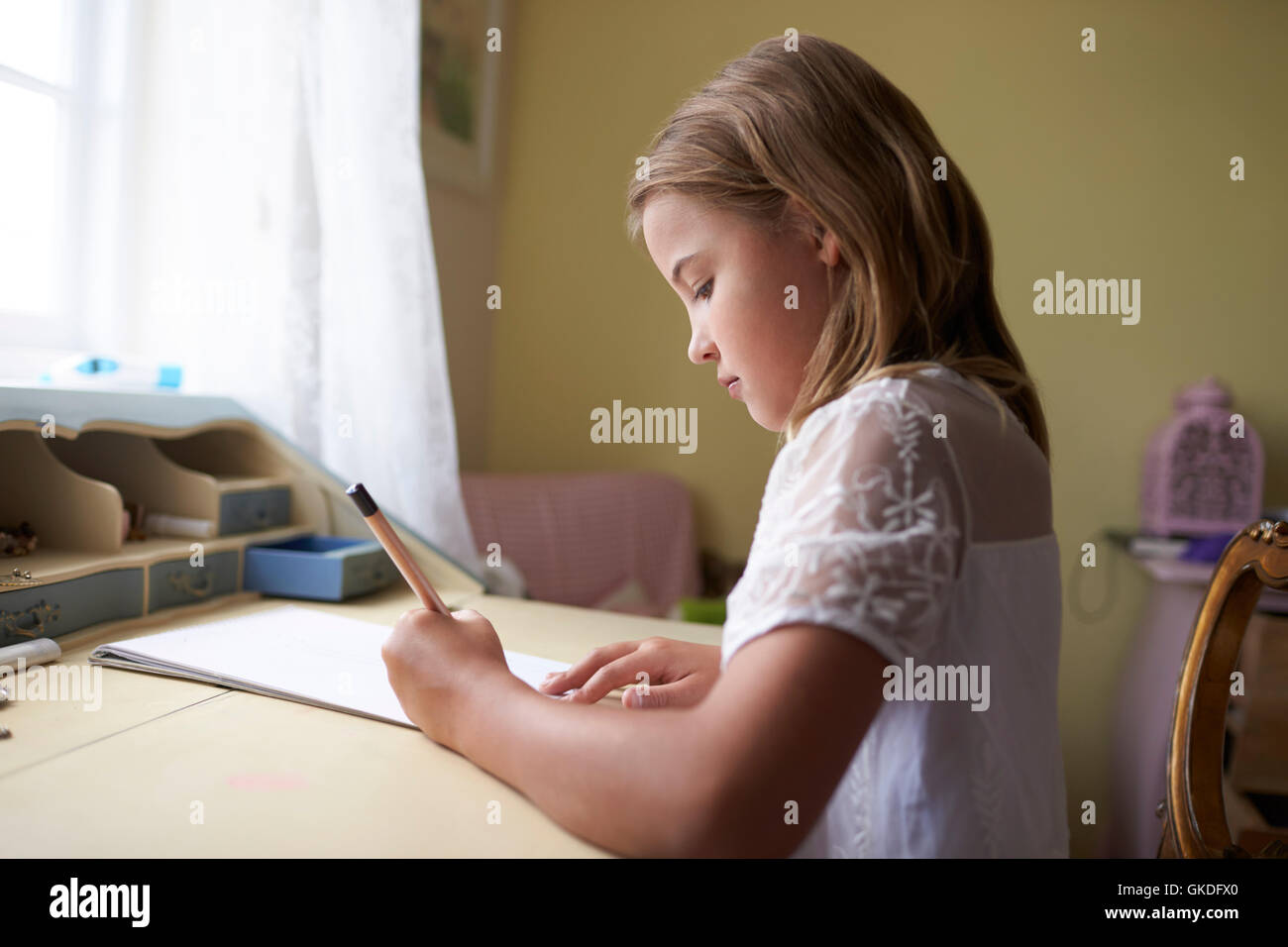 Junges Mädchen am Schreibtisch sitzen und schreiben im Schlafzimmer Stockfoto