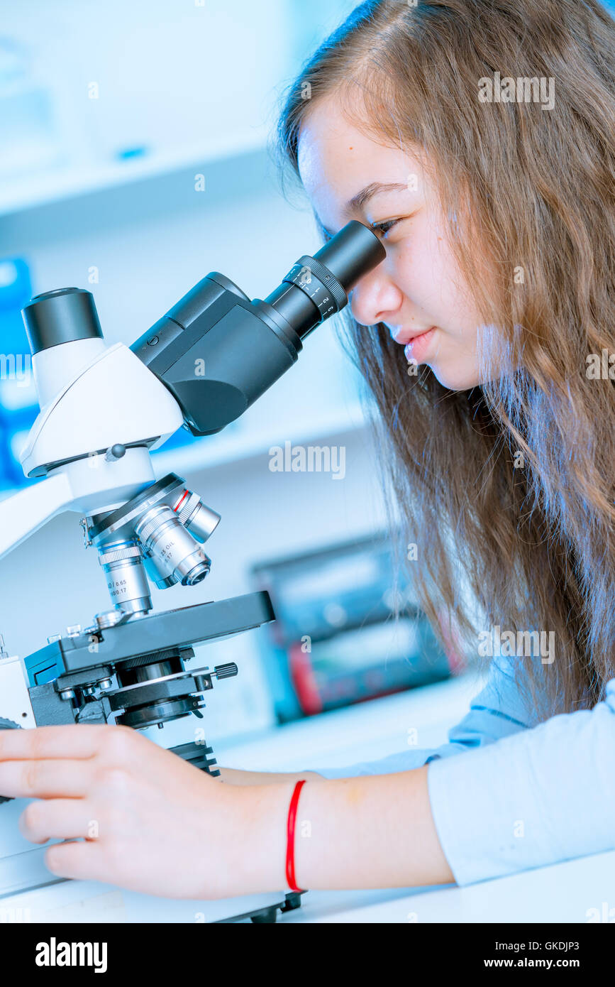 Junge Frau Schülerarbeiten im mikrobiologischen Labor mit Mikroskop Stockfoto