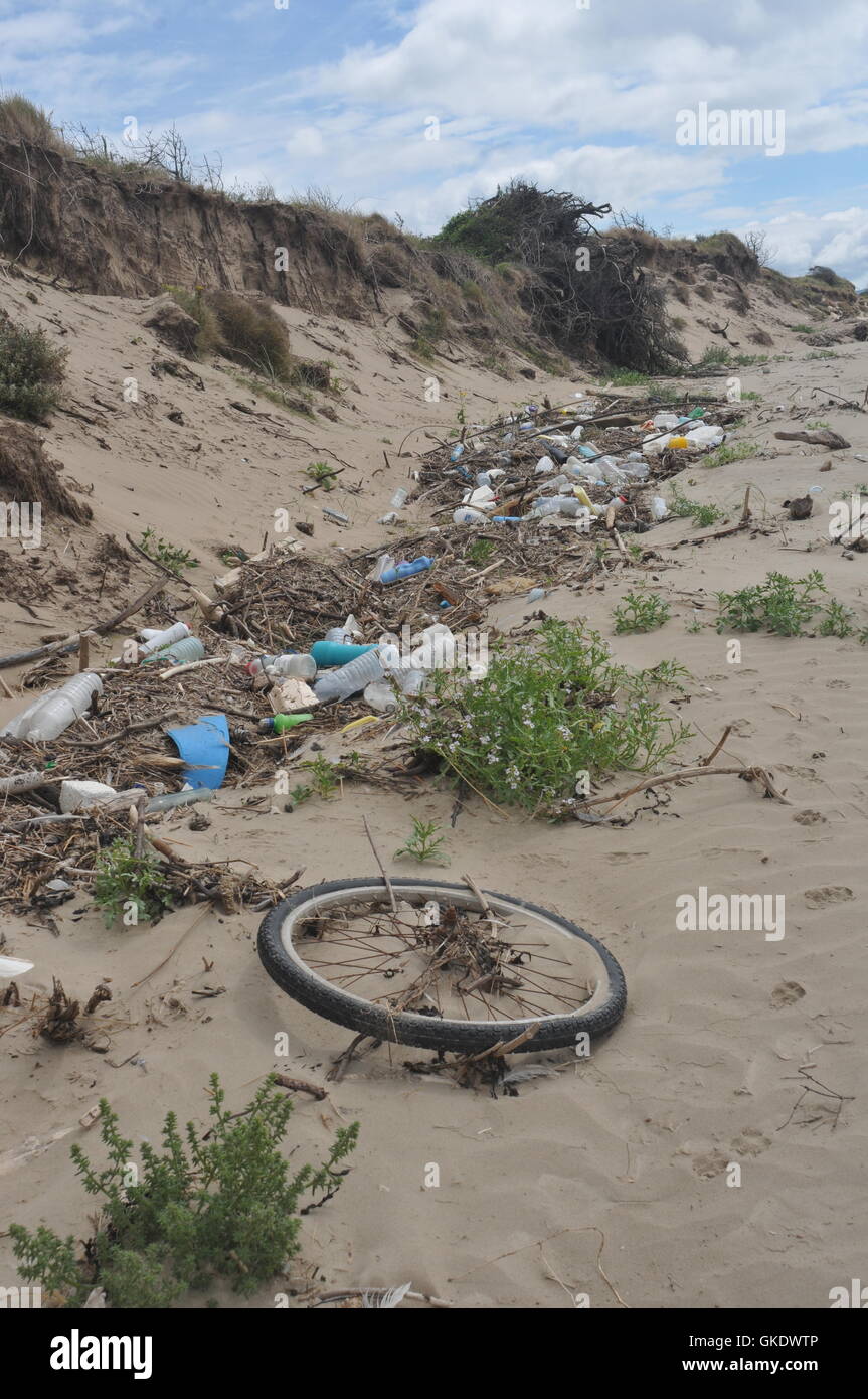 Dies ist Müll auf einem sandigen Strand, einschließlich Kunststoff-Flaschen gewaschen, ein Fahrrad-Rad, Seil, Lebensmittelbehälter Stockfoto
