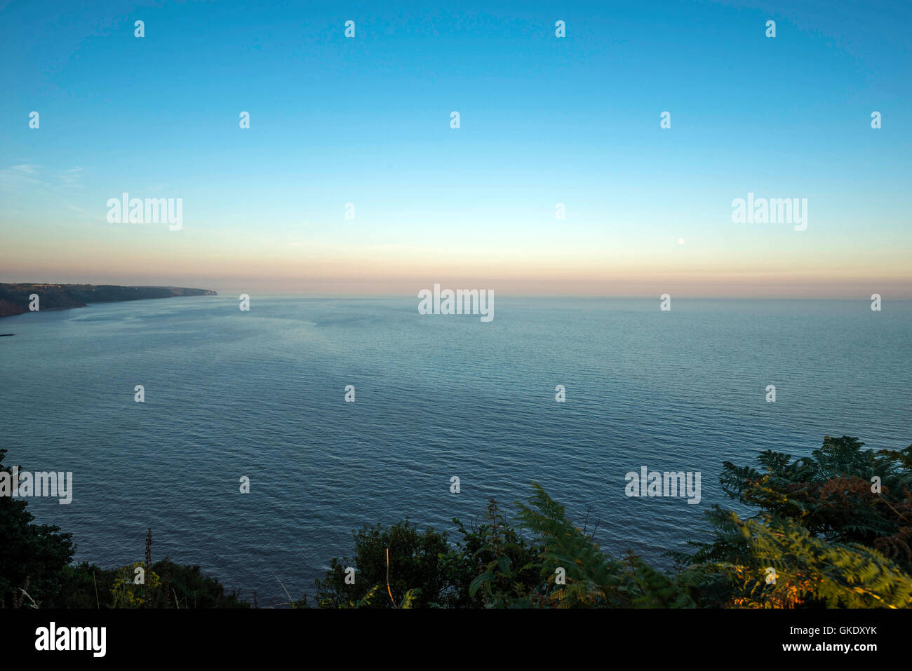 Landschaft mit dem Sonnenuntergang und Mond Aufstieg entlang der Jurassic Coast in der Nähe der Küstenstadt am Meer Stadt Sidmouth. Stockfoto