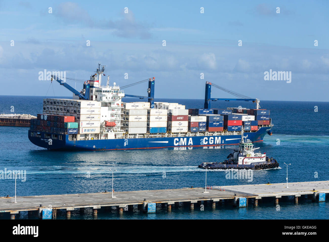 Ein großer Schlepper entlang eine riesige, geladene CMA CGM-Frachter in St. Maarten Stockfoto